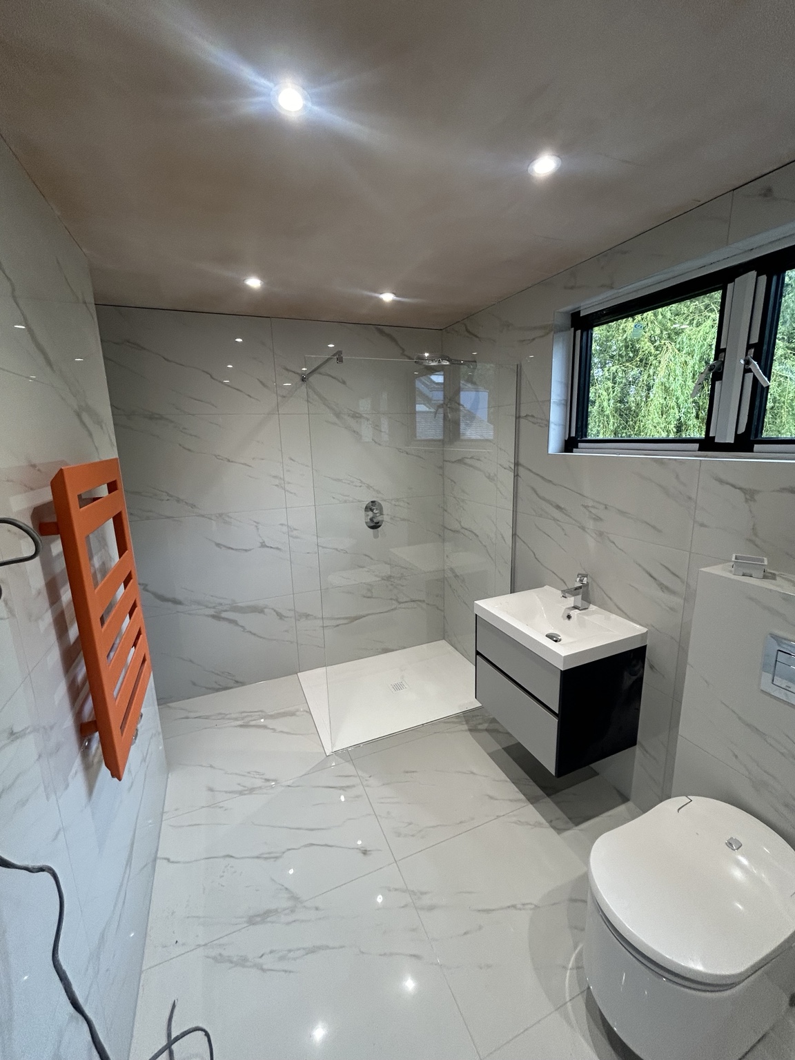 JMB bathroom installation with marble-effect wall and floor tiling
